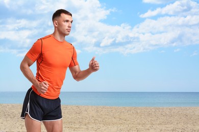 Image of Sporty man running on beach. Space for text