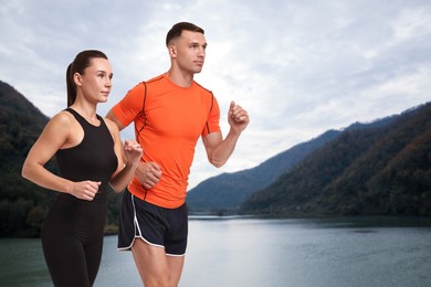 Sporty couple running near lake. Space for text