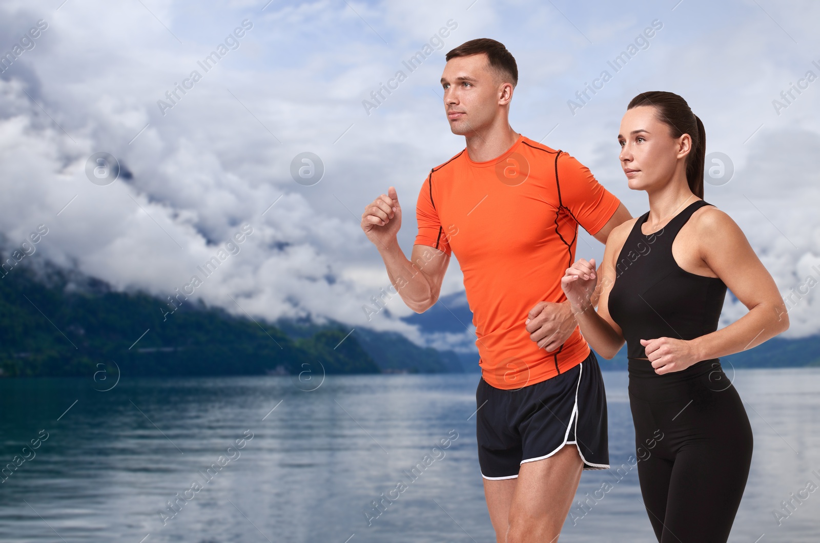 Image of Sporty couple running near lake. Space for text