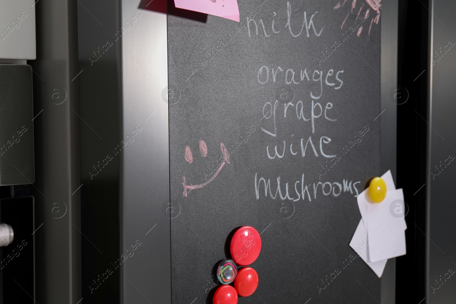 Photo of Magnetic board with shopping list and notes on refrigerator in kitchen