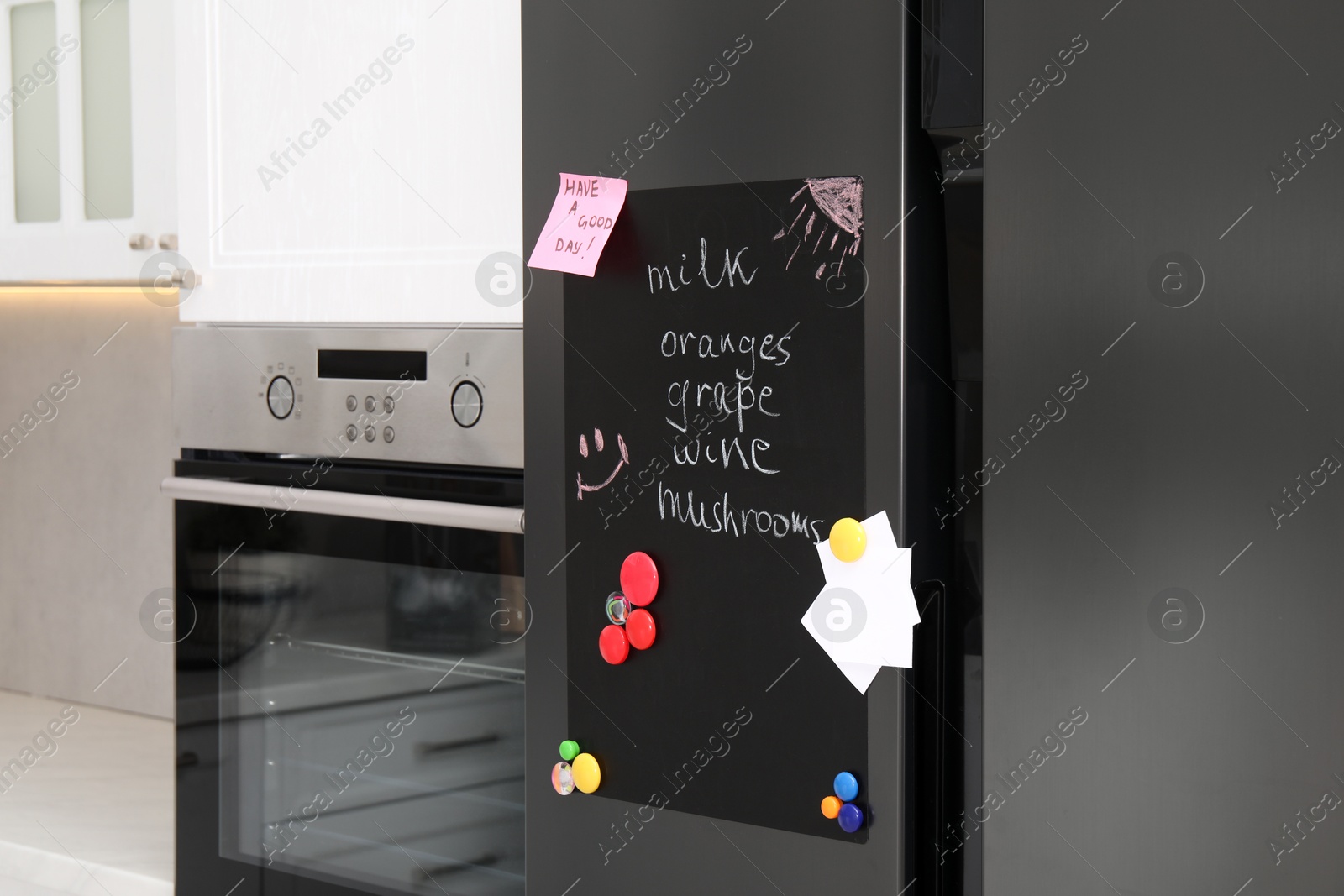 Photo of Magnetic board with shopping list and notes on refrigerator in kitchen