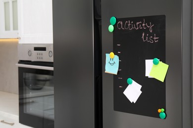 Photo of Magnetic board with activity list and notes on refrigerator in kitchen