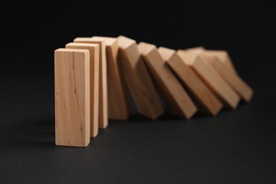 Domino effect. Wooden blocks falling on black background