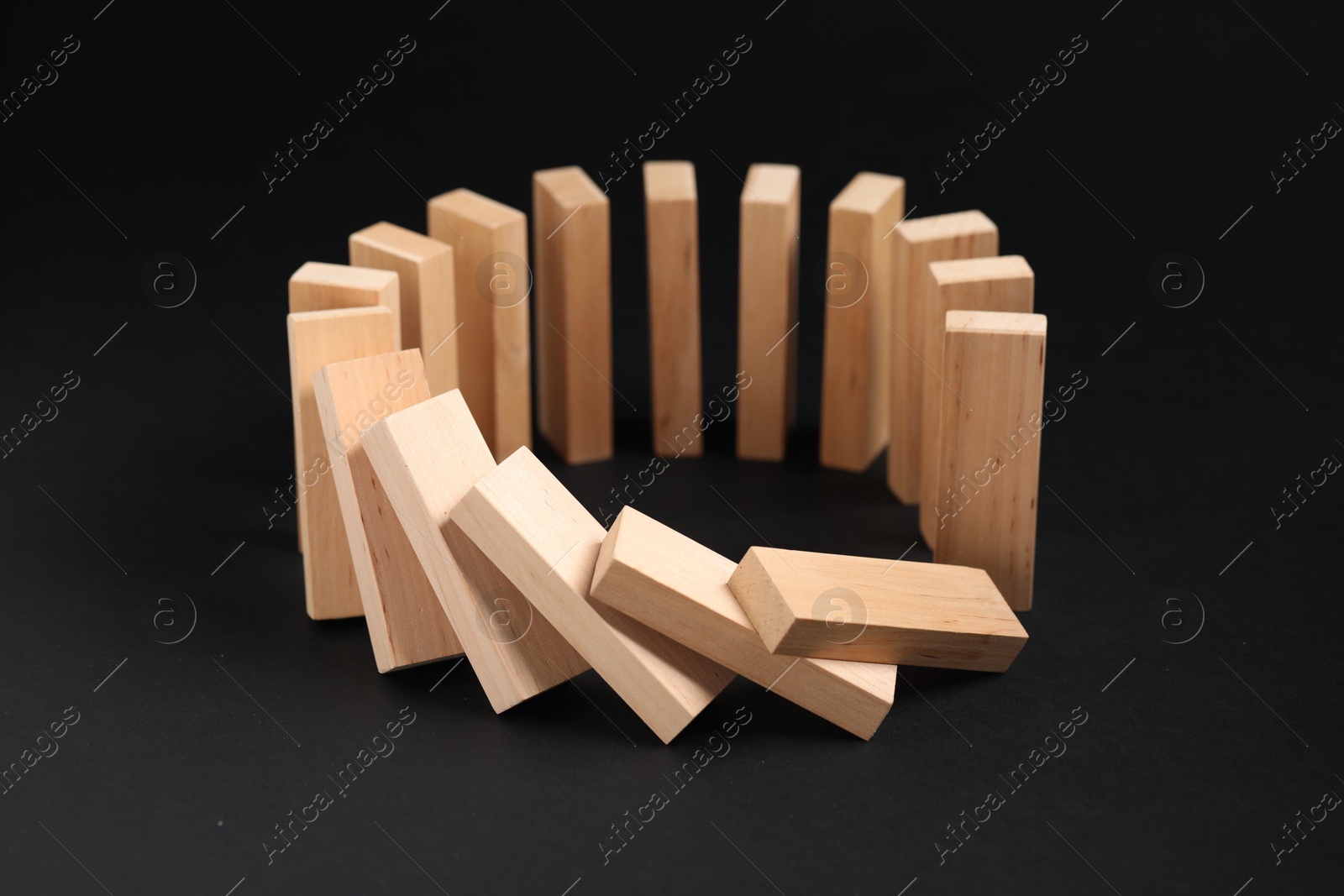 Photo of Domino effect. Wooden blocks falling on black background, closeup