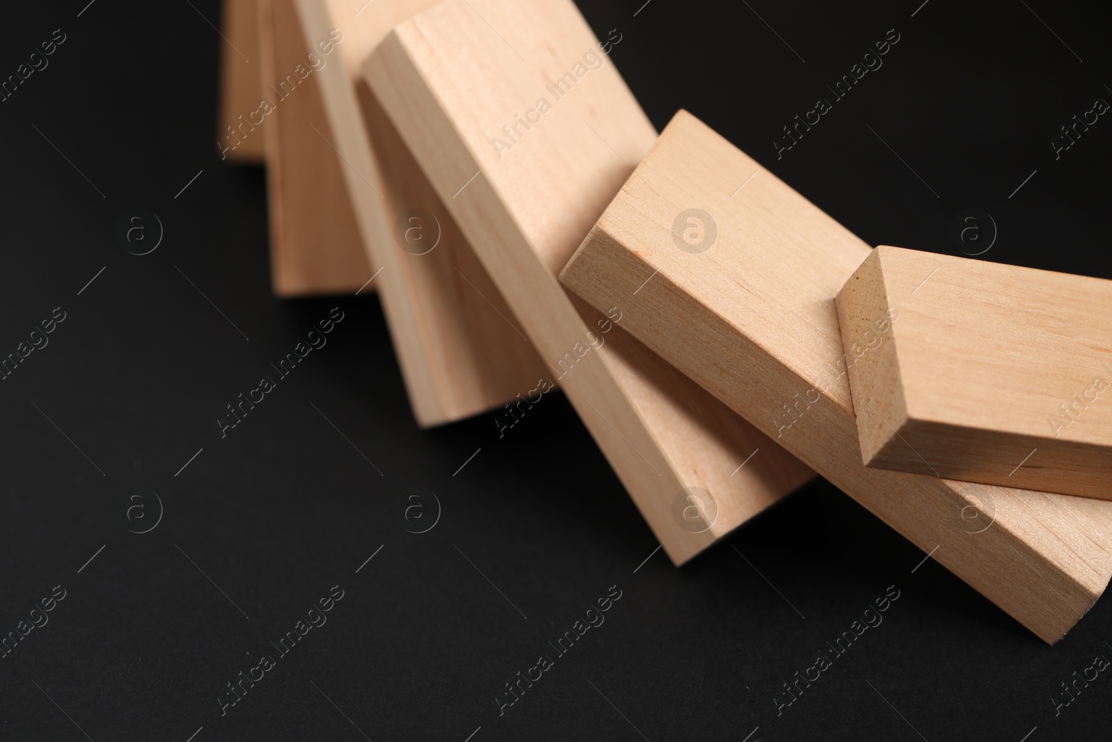 Photo of Domino effect. Wooden blocks falling on black background, closeup