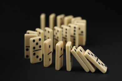 Photo of Domino effect. Tiles falling on black background