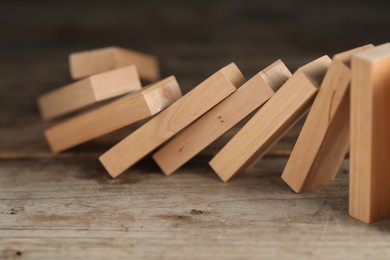 Photo of Domino effect. Wooden blocks falling on table, closeup