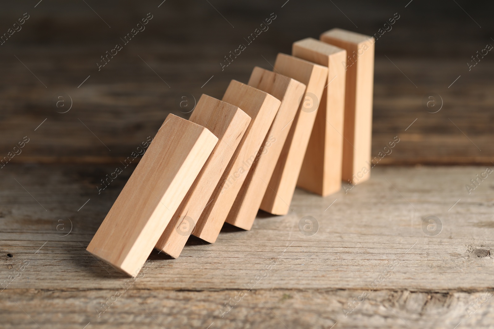 Photo of Domino effect. Wooden blocks falling on table, closeup