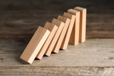 Photo of Domino effect. Wooden blocks falling on table, closeup