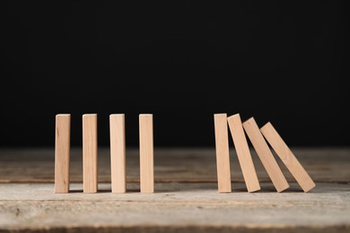 Domino effect. Wooden blocks falling on table against black background