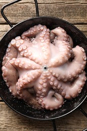 Fresh raw octopus in frying pan on wooden table, top view