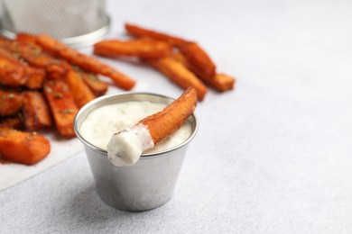 Photo of Delicious sweet potato fries and sauce on light grey table, closeup. Space for text