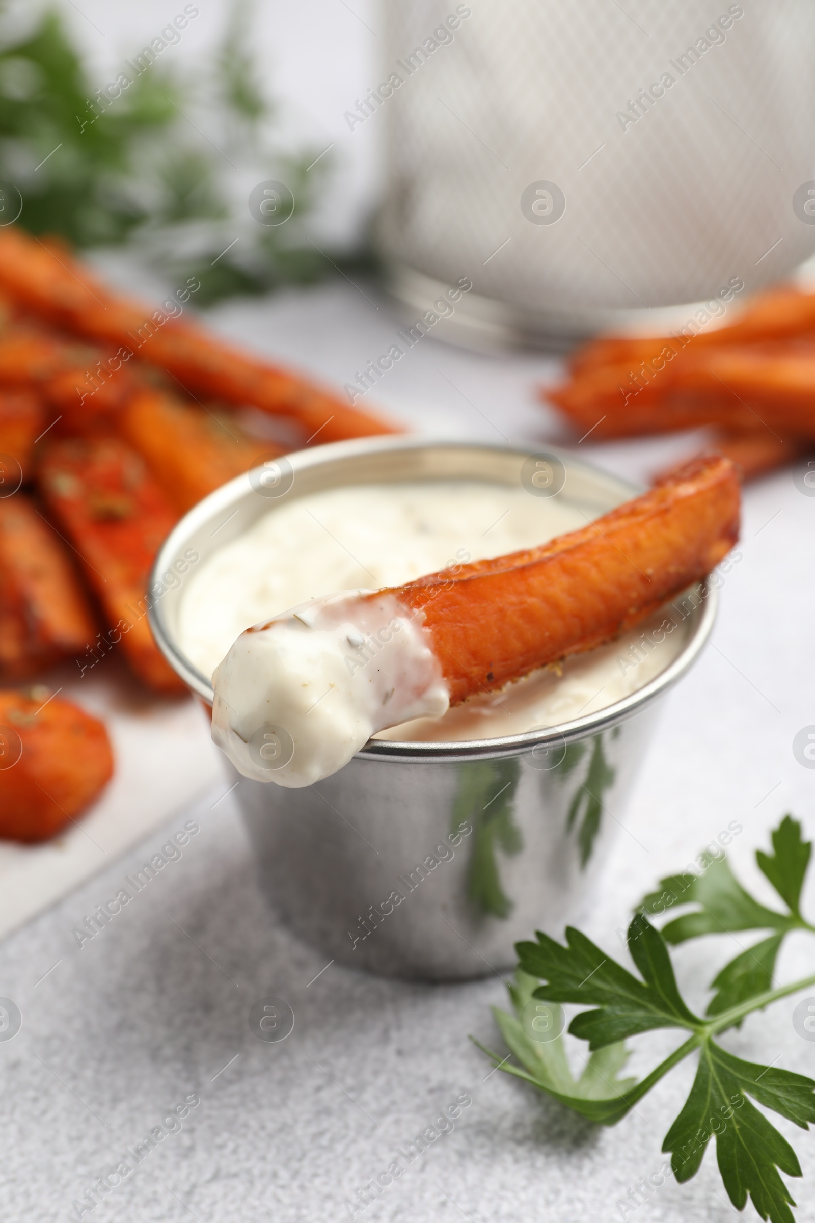 Photo of Delicious sweet potato fries, sauce and parsley on light grey table, closeup