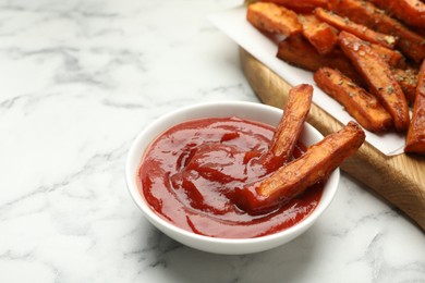 Delicious sweet potato fries with spices and sauce on white marble table, closeup