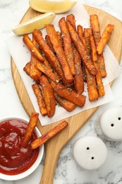 Delicious sweet potato fries with spices and sauce on white marble table, top view