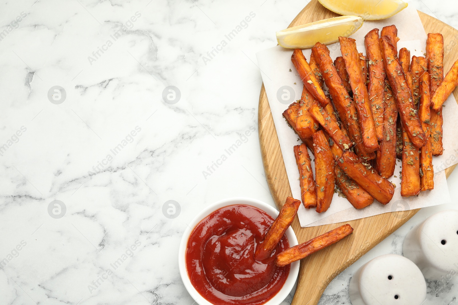 Photo of Delicious sweet potato fries with spices and sauce on white marble table, top view. Space for text