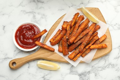 Photo of Delicious sweet potato fries with spices and sauce on white marble table, top view