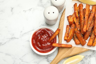 Photo of Delicious sweet potato fries with spices and sauce on white marble table, top view