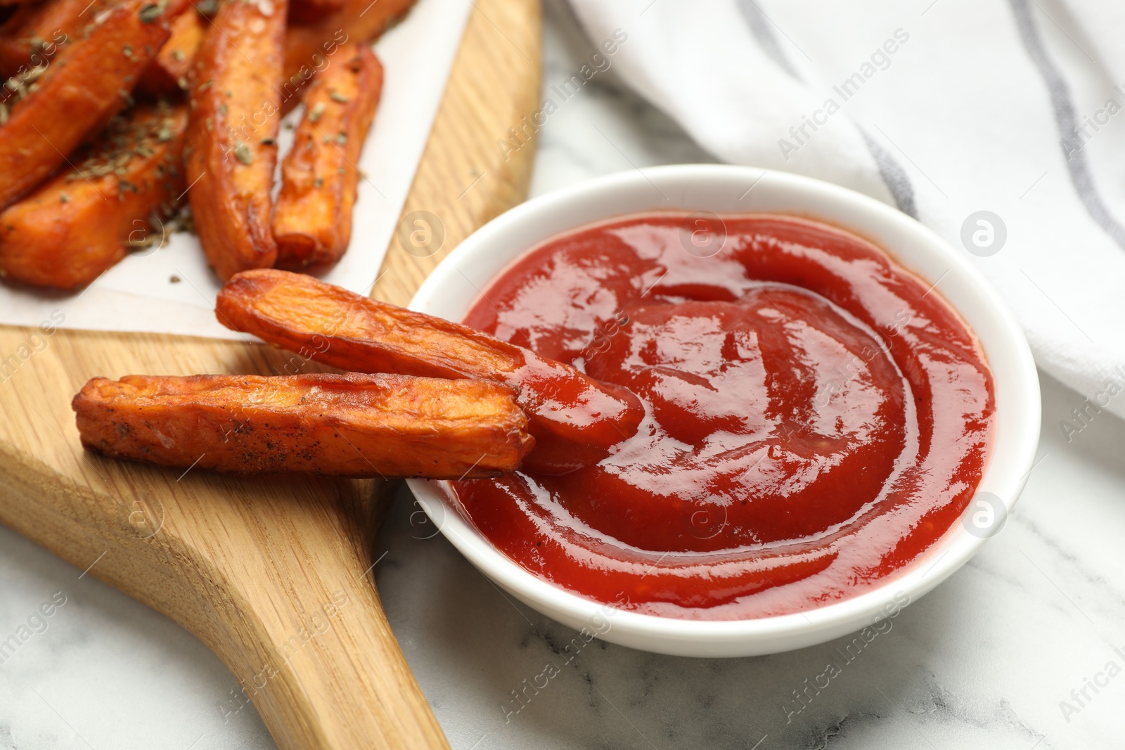 Photo of Delicious sweet potato fries with spices and sauce on white marble table, closeup