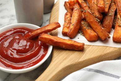 Photo of Delicious sweet potato fries with spices and sauce on white marble table, closeup