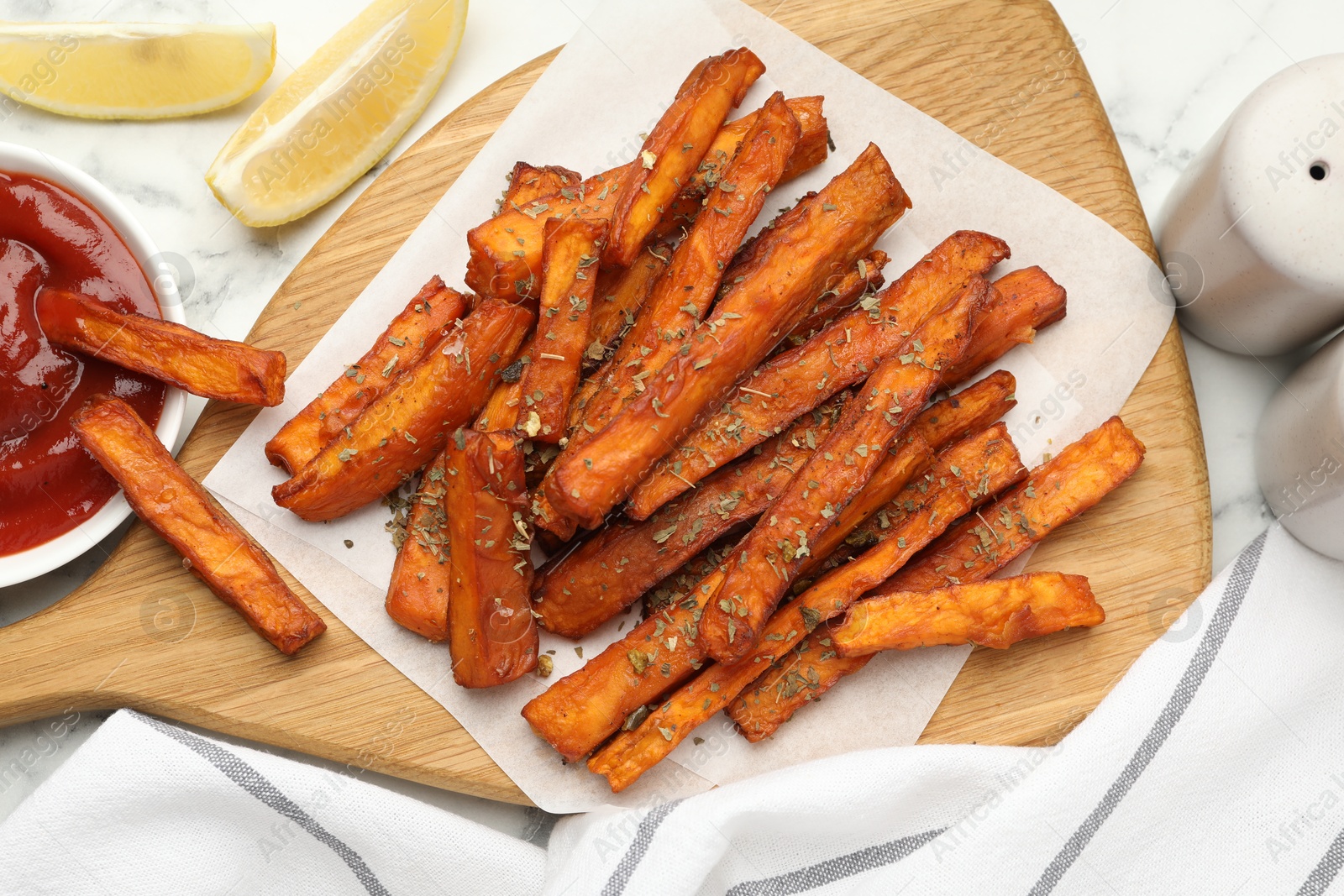 Photo of Delicious sweet potato fries with spices and sauce on white marble table, top view