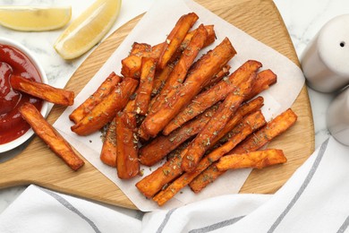 Photo of Delicious sweet potato fries with spices and sauce on white marble table, top view