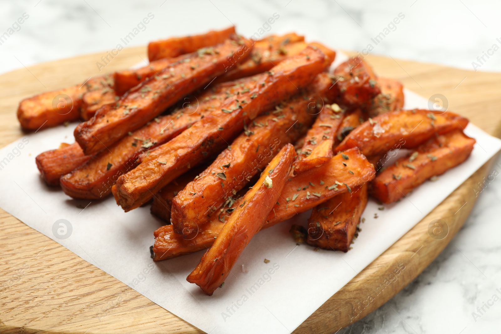 Photo of Delicious sweet potato fries with spices on table, closeup