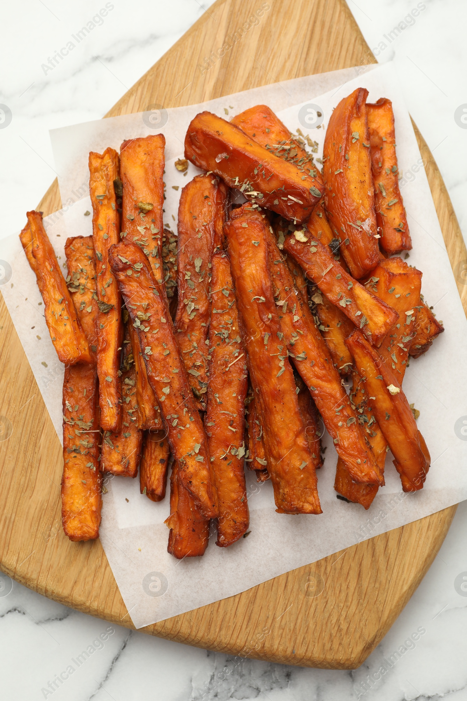 Photo of Delicious sweet potato fries with spices on white marble table, top view