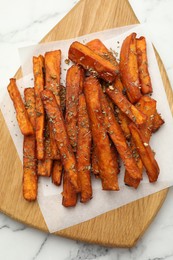 Photo of Delicious sweet potato fries with spices on white marble table, top view