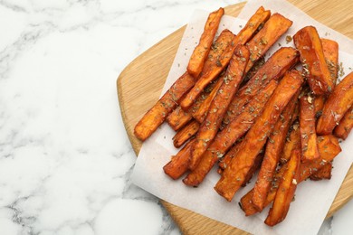 Photo of Delicious sweet potato fries with spices on white marble table, top view. Space for text