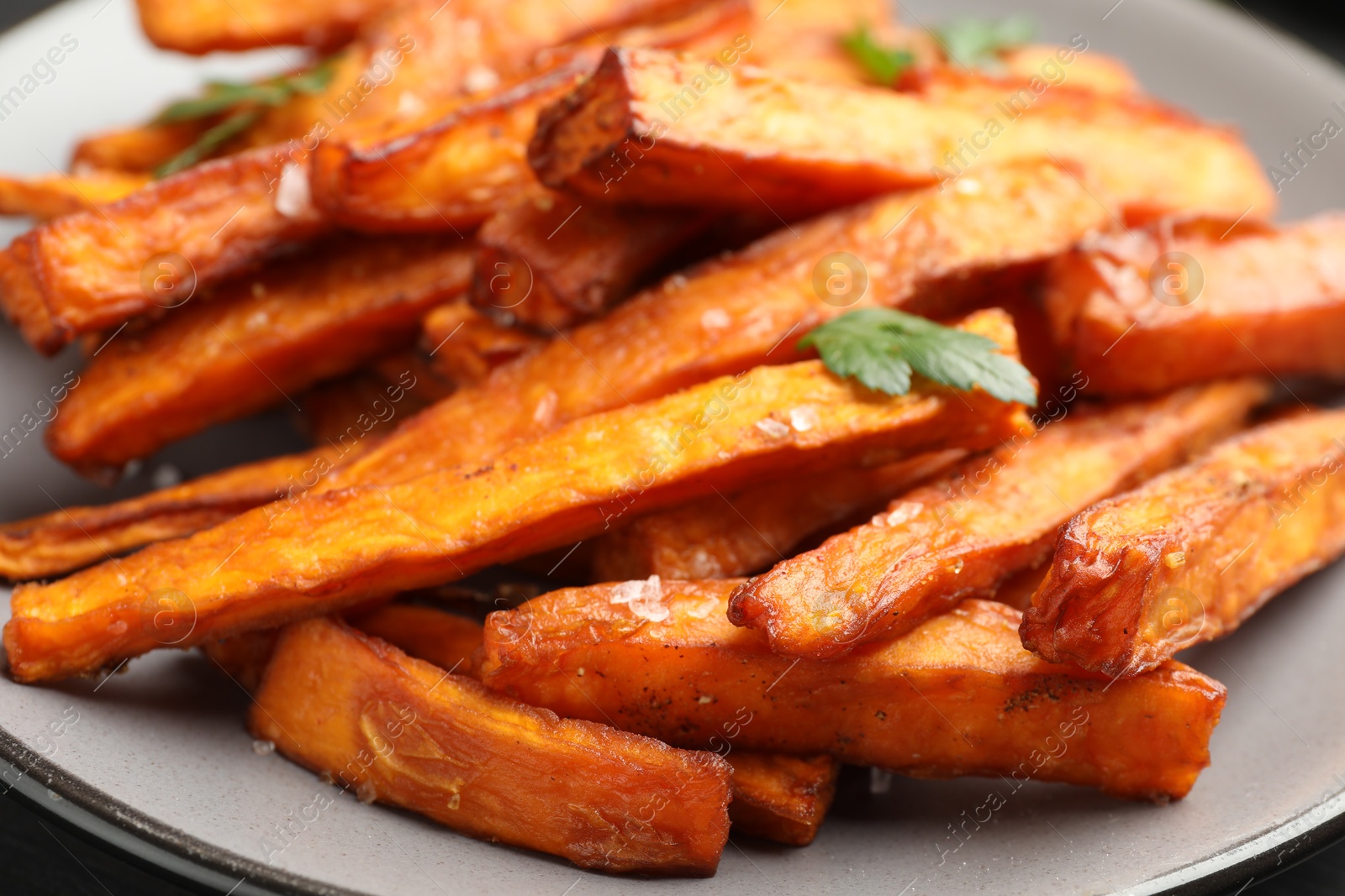 Photo of Delicious sweet potato fries with spices on plate, closeup