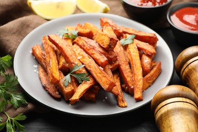 Photo of Delicious sweet potato fries with spices and sauces on table, closeup