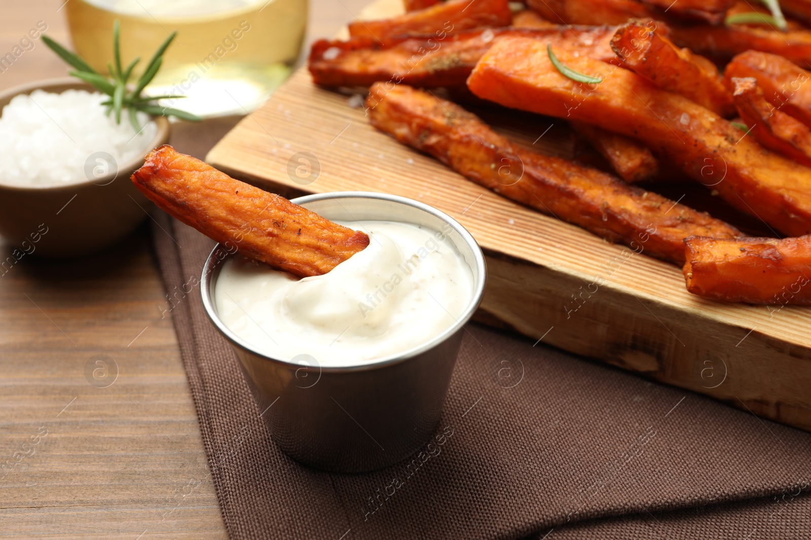 Photo of Delicious sweet potato fries and sauce on wooden table, closeup