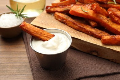 Delicious sweet potato fries and sauce on wooden table, closeup