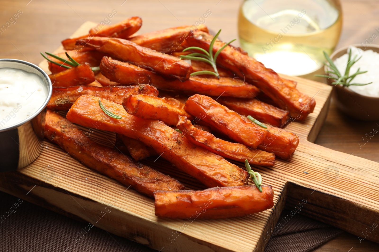 Photo of Delicious sweet potato fries with spices, sauce and oil on table, closeup