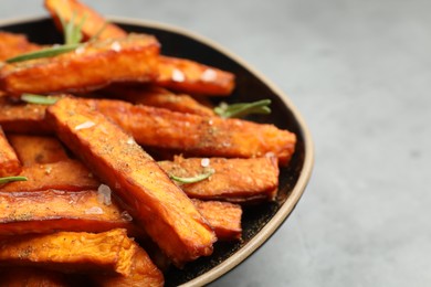 Photo of Delicious sweet potato fries with spices in bowl on grey table, closeup. Space for text