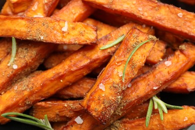 Delicious sweet potato fries with spices as background, closeup