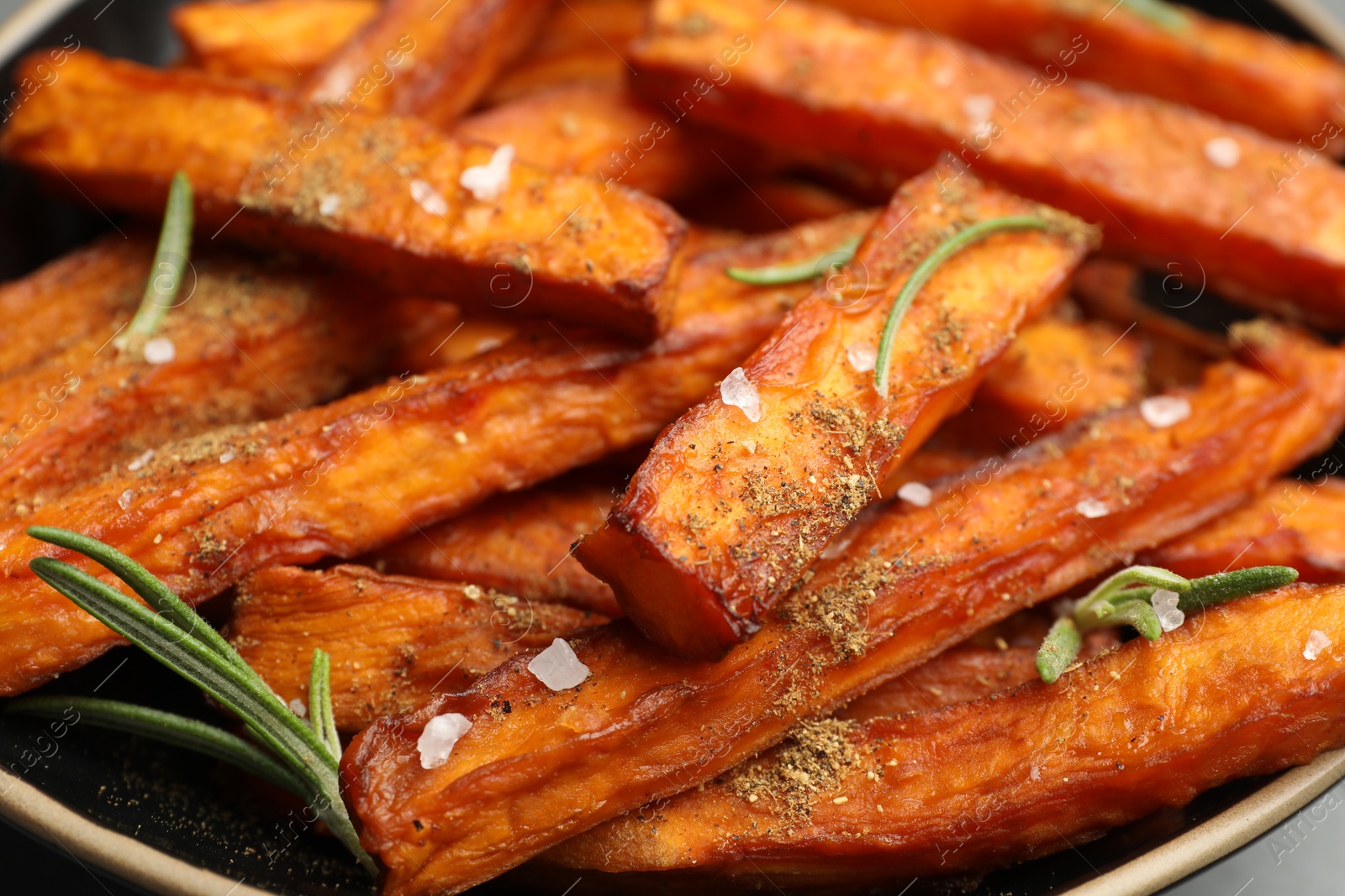 Photo of Delicious sweet potato fries with spices in bowl, closeup