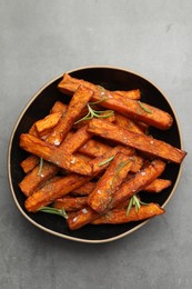 Delicious sweet potato fries with spices in bowl on grey table, top view