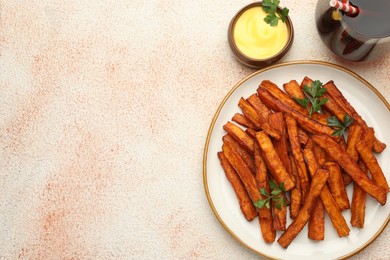 Photo of Delicious sweet potato fries, parsley, sauce and soda drink on beige textured table, top view. Space for text