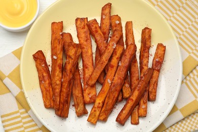 Photo of Delicious sweet potato fries and sauce on table, top view