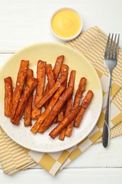 Photo of Delicious sweet potato fries and sauce on white wooden table, top view