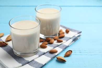 Glasses of almond milk and nuts on blue wooden table