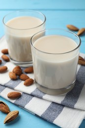 Photo of Glasses of almond milk and nuts on blue wooden table, closeup