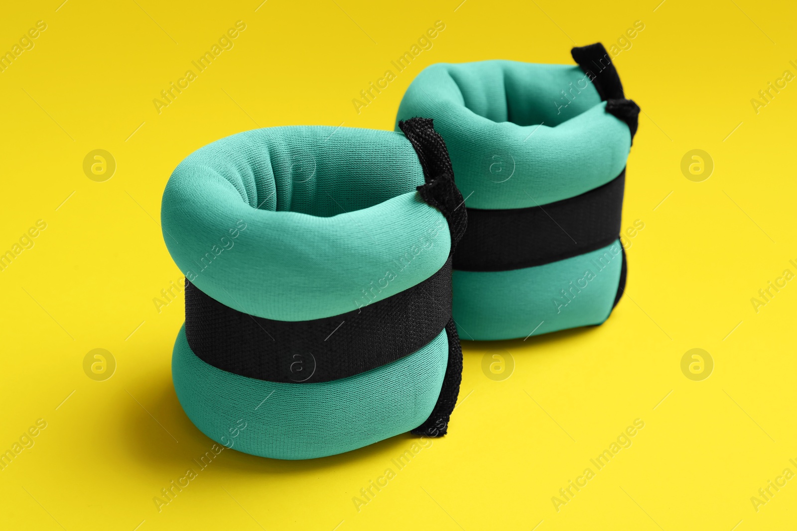 Photo of Stylish turquoise ankle weights on yellow background