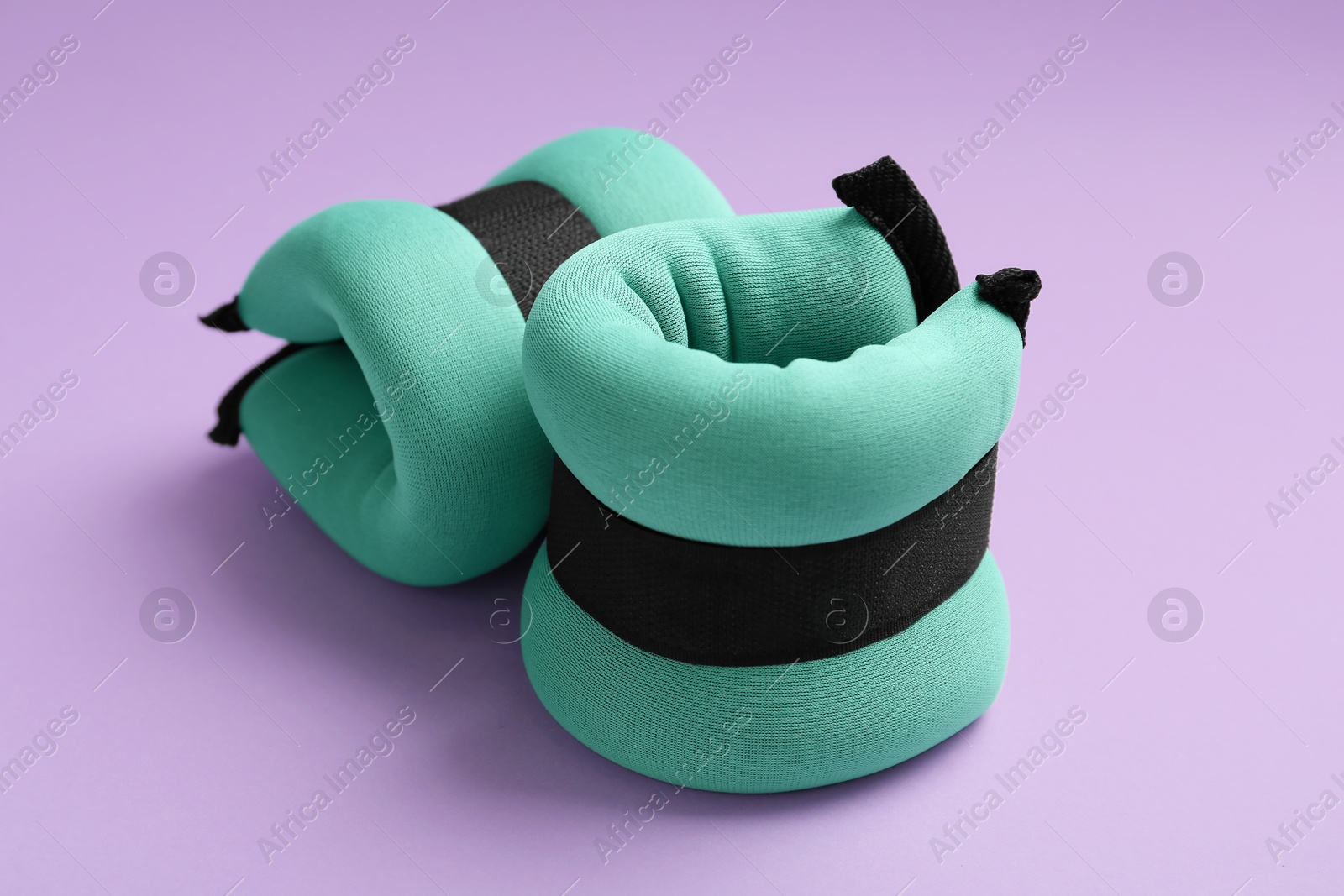 Photo of Stylish turquoise ankle weights on violet background