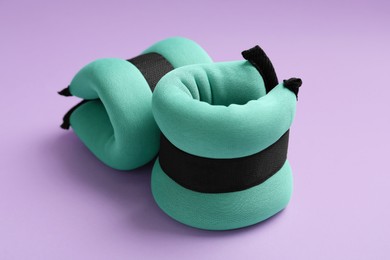 Stylish turquoise ankle weights on violet background