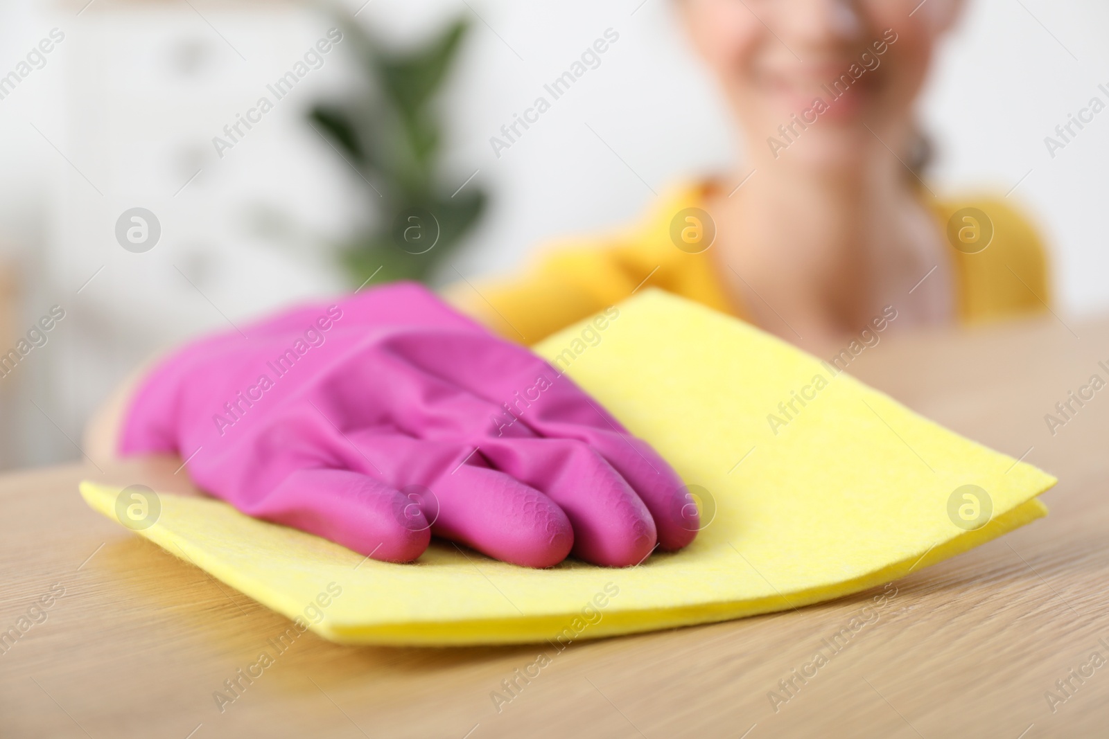 Photo of Woman cleaning table with rag at home, selective focus