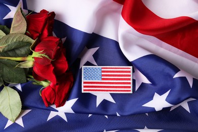 Photo of Veterans day. American army patch and rose flowers on USA flag, flat lay