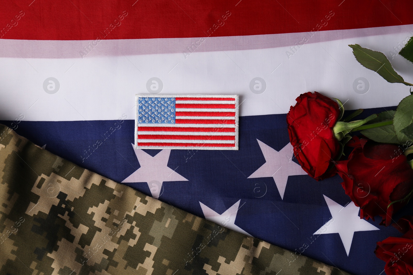 Photo of Veterans day. USA army patch, rose flowers and military uniform on American flag, flat lay